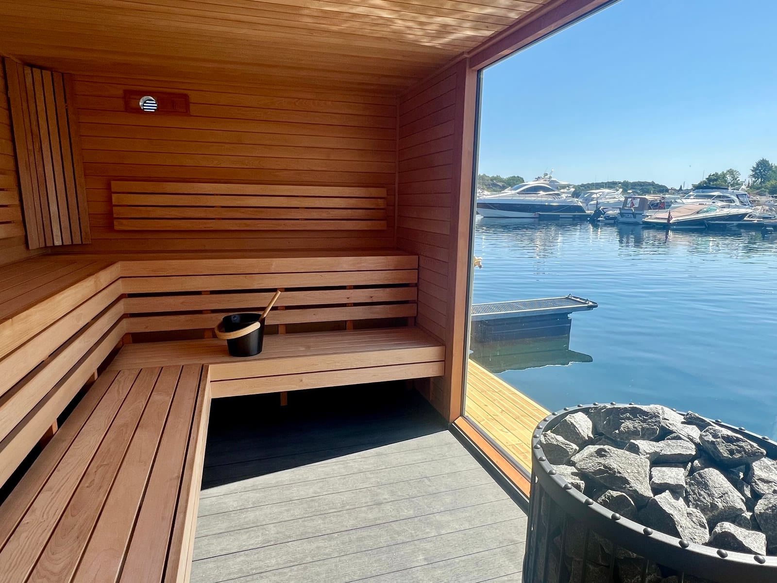 The sauna's L-shaped bench with a view of the harbour through the panoramic window
